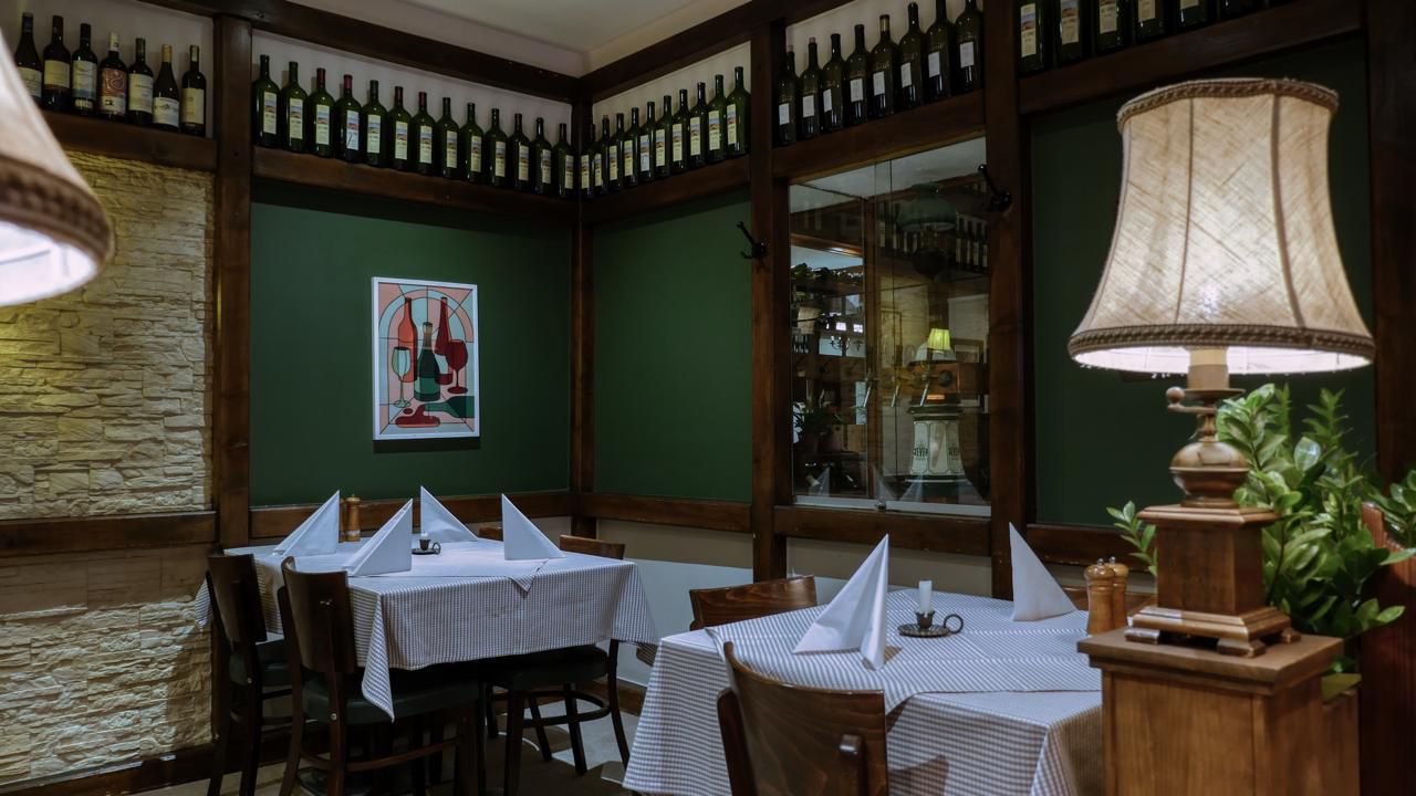 Essbereich mit tiefgrünen Wänden und Weinpräsentation